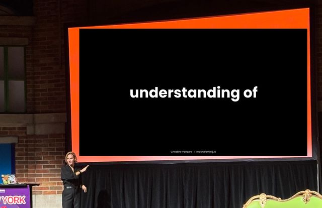 Christine Vallaure on stage in front of a (photo-shopped) slide that says understanding of.
